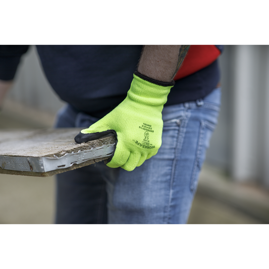 Person wearing a bright green glove holding a wooden pallet.