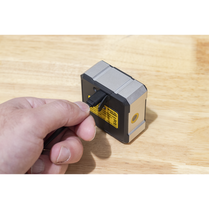 Hand holding a small electronic device on a wooden surface